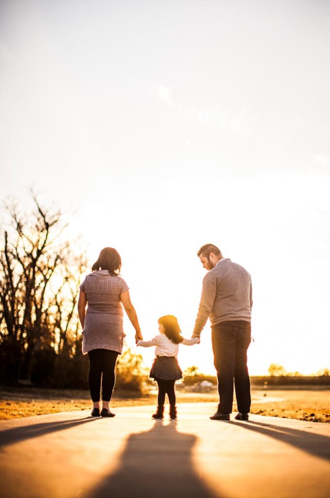 A family of three walks hand in hand at sunset, enjoying togetherness and warmth.